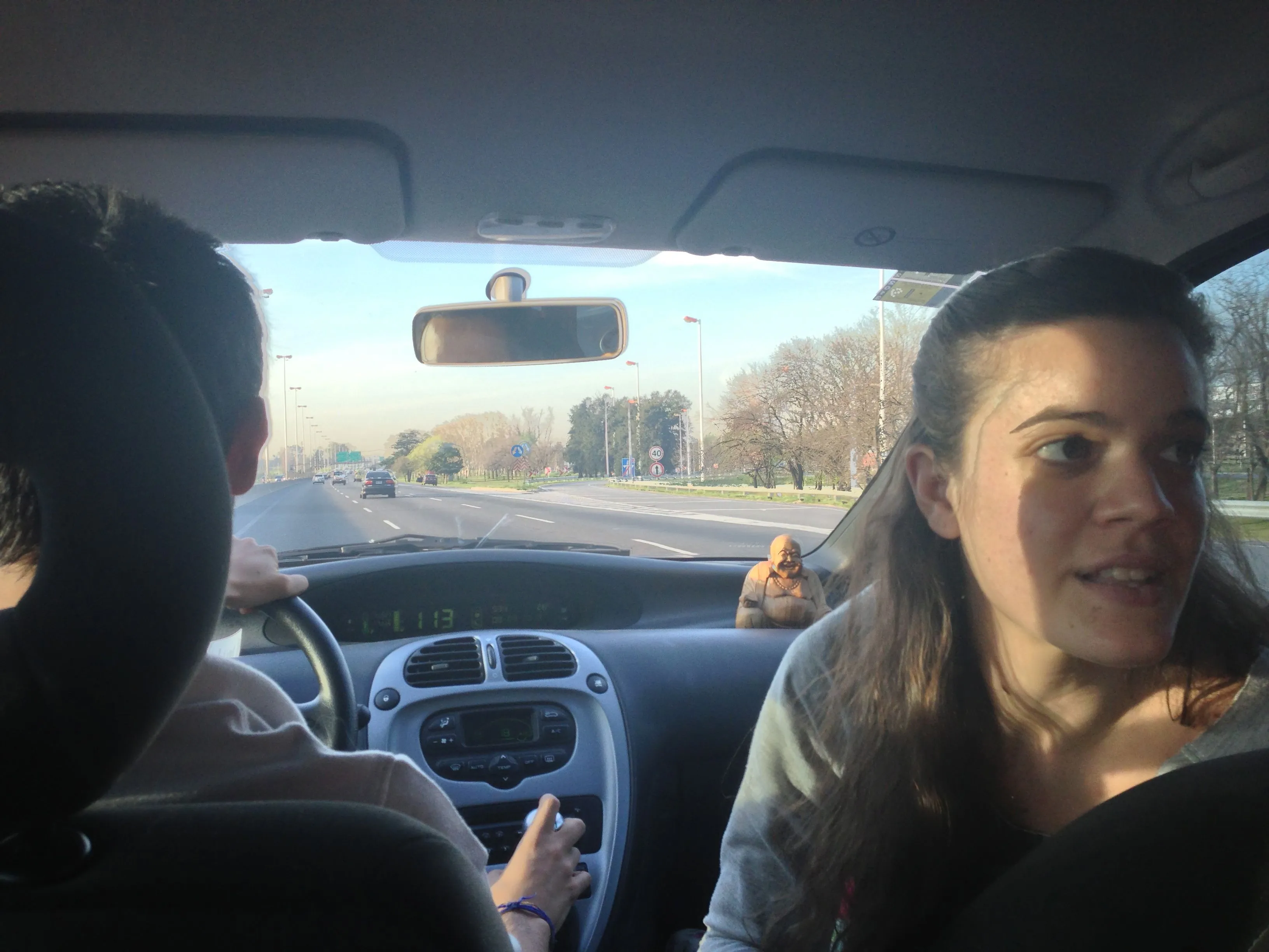 Ana turned toward the back seat while Diego drives along a highway