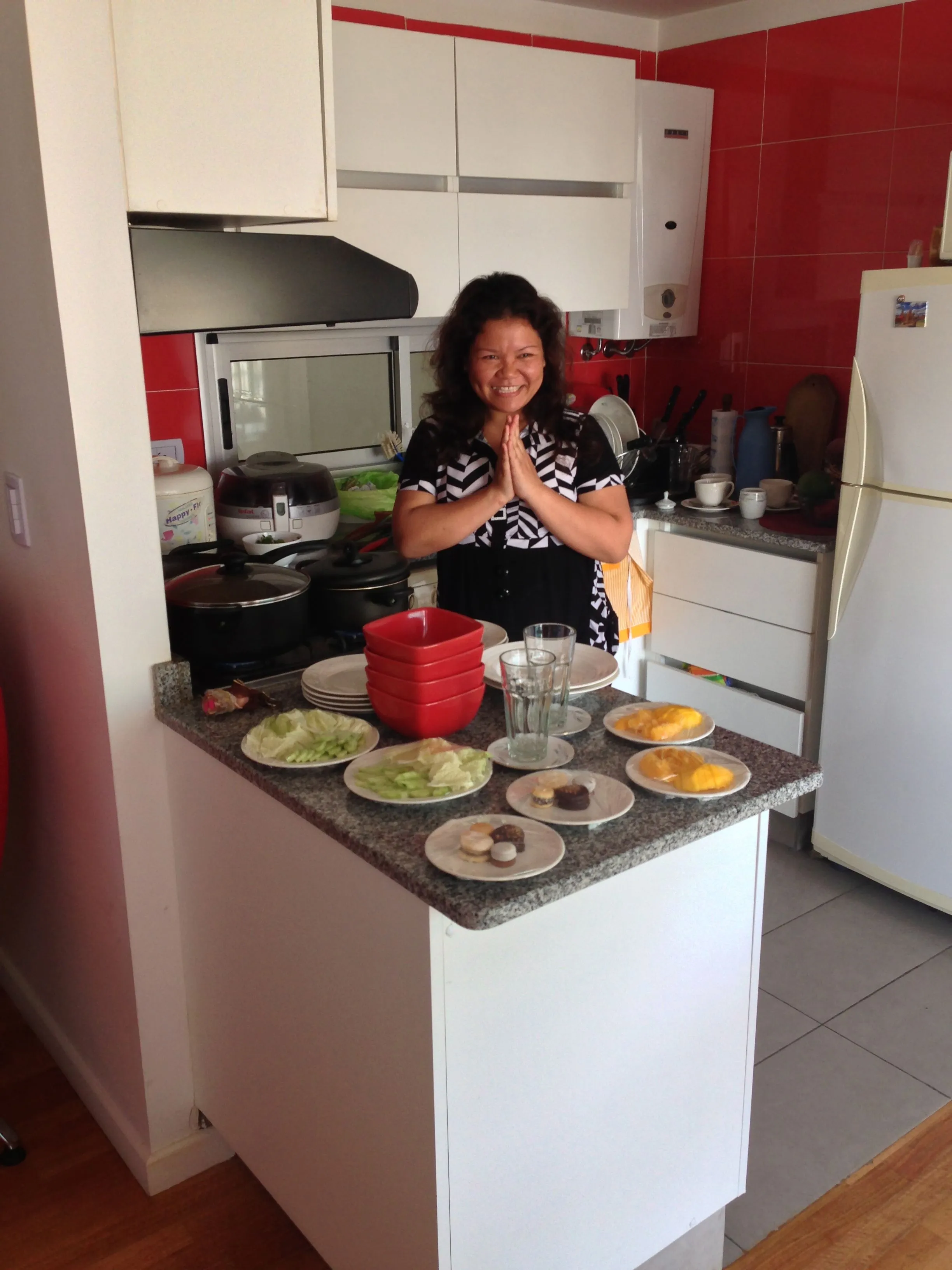 Omjai smiling with her hands together in a kitchen
