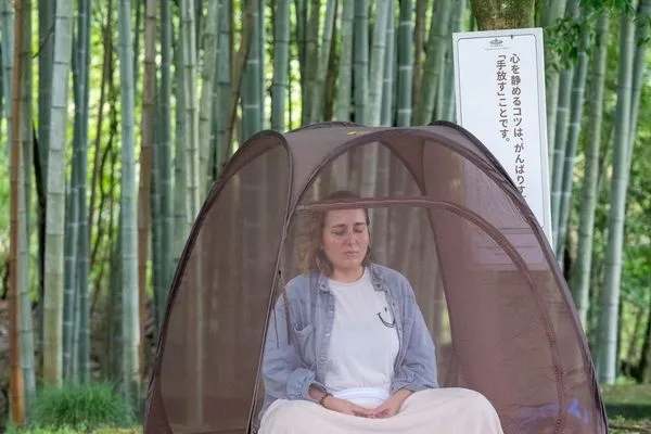 A participant meditating in a tent among the bamboo