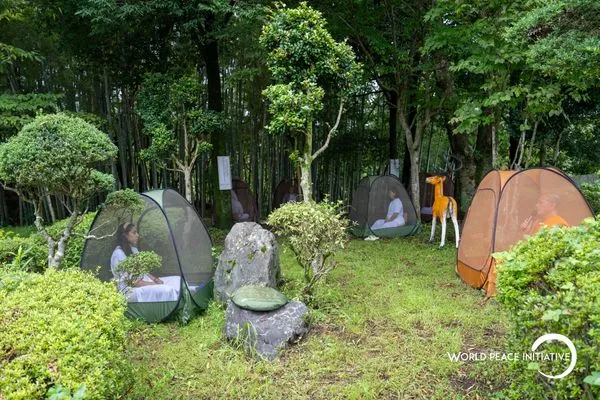 Tents scattered through the garden, everyone sitting alone together