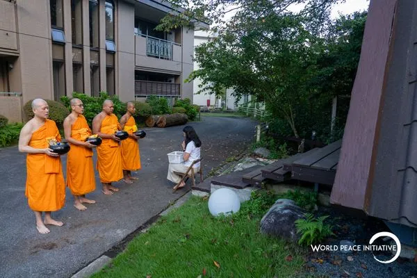 Monks standing with alms bowls as a participant offers food